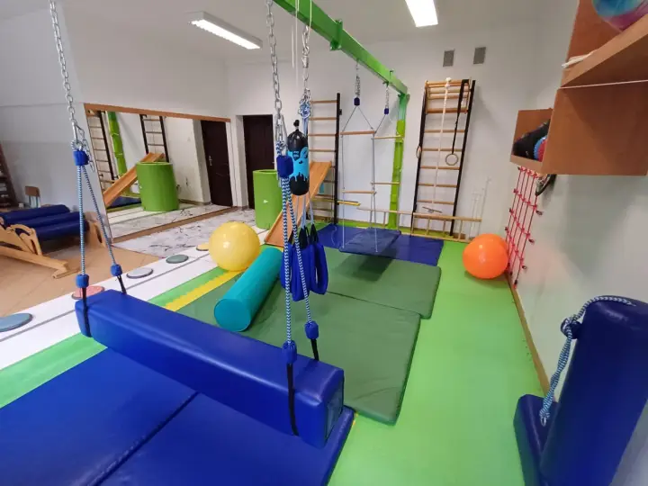 Sala terapeutyczna z huśtawkami, materacami i sprzętem do ćwiczeń, wspierająca rozwój dzieci z zaburzeniem integracji sensorycznej.
